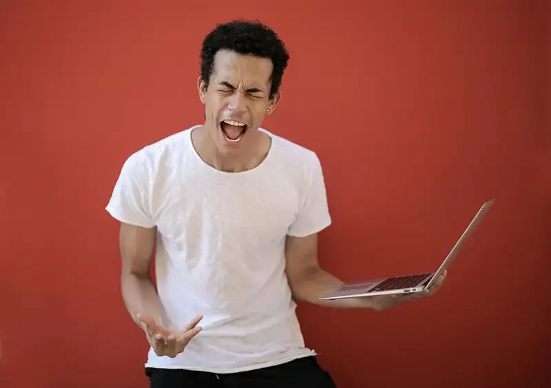 Person skriker frustrert med laptop